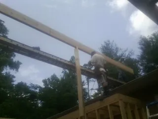 Carpenter setting a ridge beam over a new addition frame — Ice Dam Removal by Roofing Brothers in Twin City