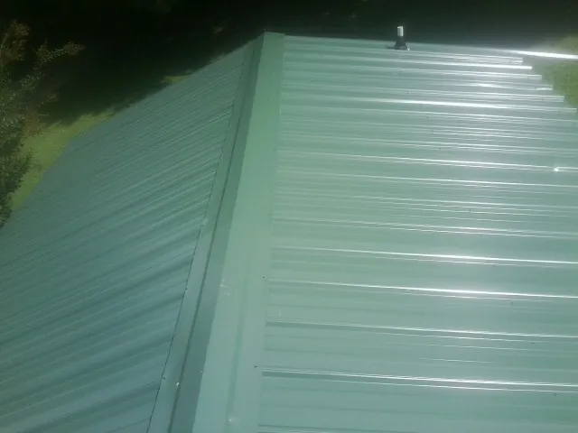 New green metal panels meeting at the ridge of a roof — Flat Roof Repair work by our crew in Twin City