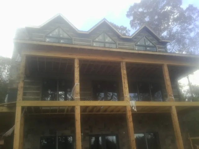Dormers and porch framing on a large log home under construction — Roof Coating work by our crew in Twin City