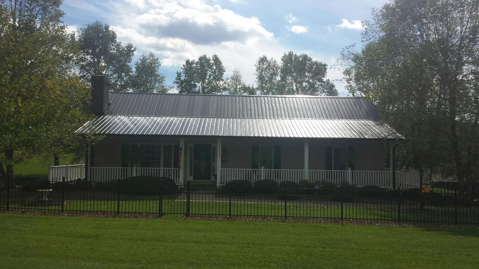 Gray metal roof on a brick ranch with a full width front porch — Gutter Guard Installation work by our crew in Twin City