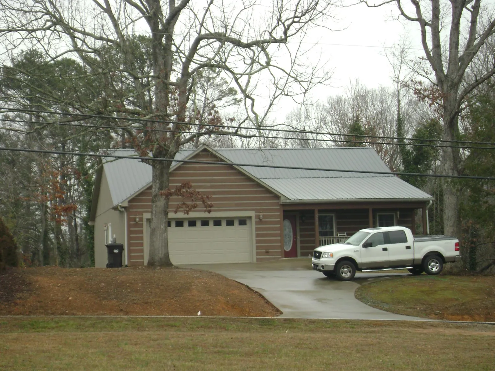 Gray metal roof on a log sided house with an attached two car garage in Twin City