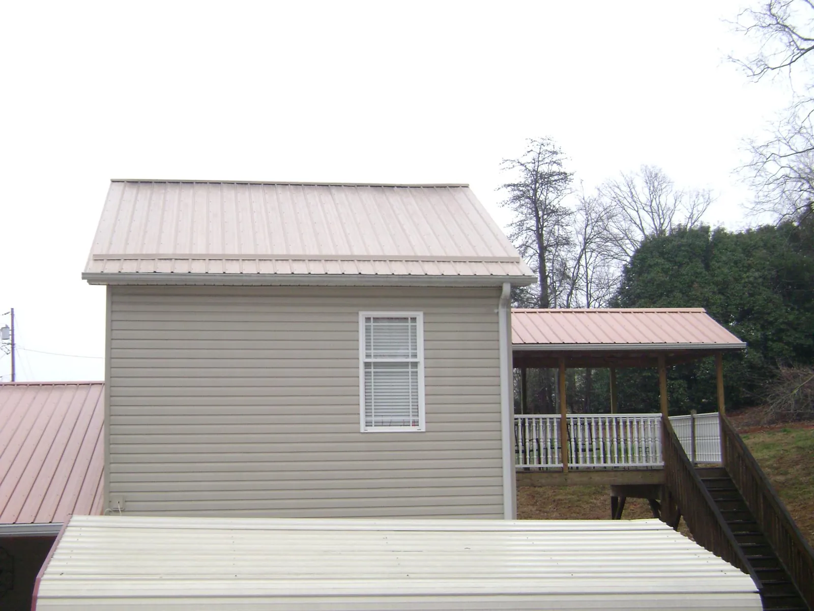 Tan metal roofs on a two story addition and attached porch, from a Roof Replacement job in Twin City