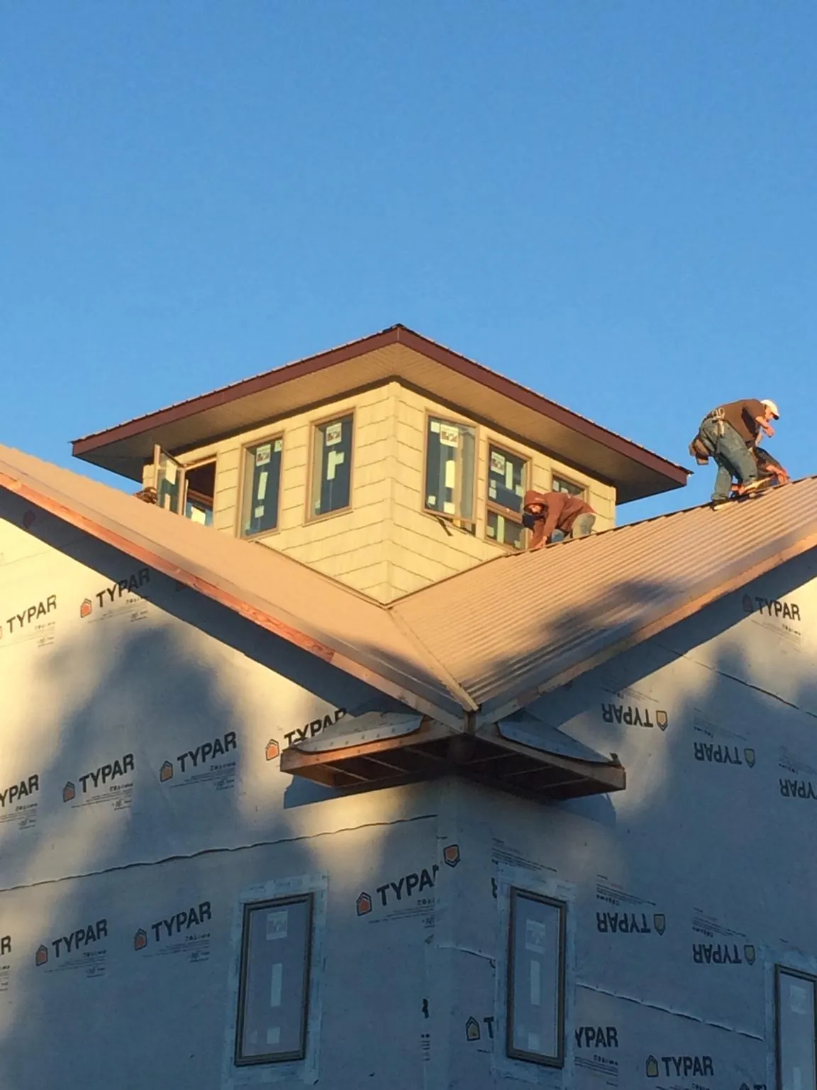 Roofers working around a rooftop cupola on a new metal roof at sunset — Roof Waterproofing in Twin City by Roofing Brothers